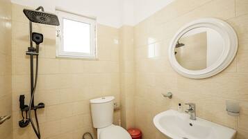 Un baño con inodoro, lavamanos, espejo y ducha.
