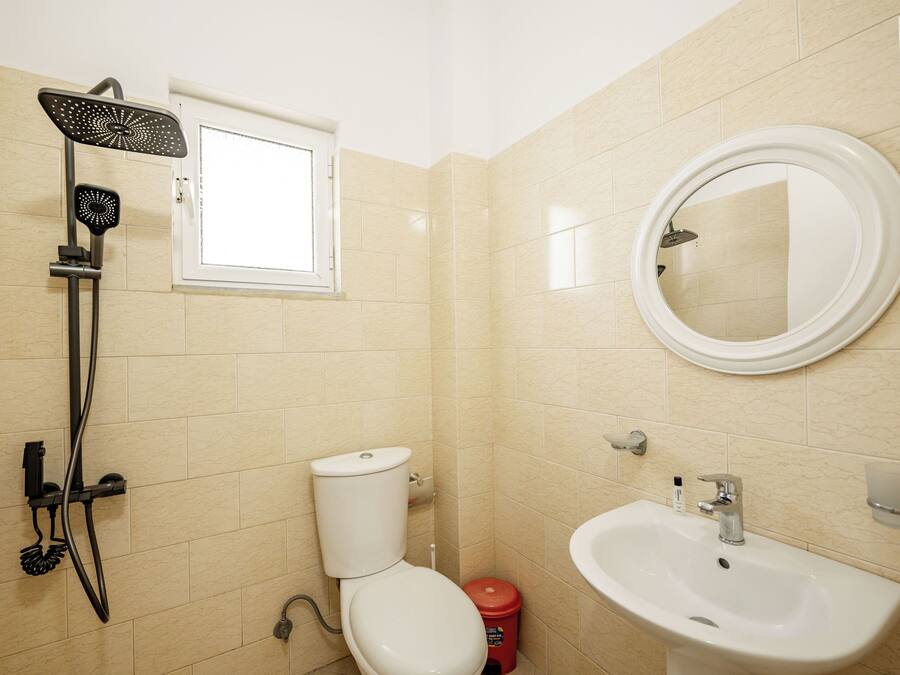 Un baño con inodoro, lavamanos, espejo y ducha.