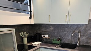 A compact kitchen with a built-in oven, a stovetop, and a sink. - Quiet, small house in the hills above Toulon, close to all amenities. (LE REVEST LES EAUX)