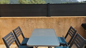 A patio with a table and four chairs, a stone floor, and a view of mountains. - Quiet, small house in the hills above Toulon, close to all amenities. (LE REVEST LES EAUX)