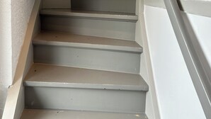 Eine Treppe mit Geländer auf der rechten Seite, die zu einer Zwischenebene führt.