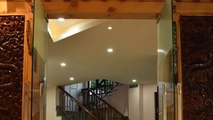 A modern interior with a glass door entrance, a staircase, and a polished floor.