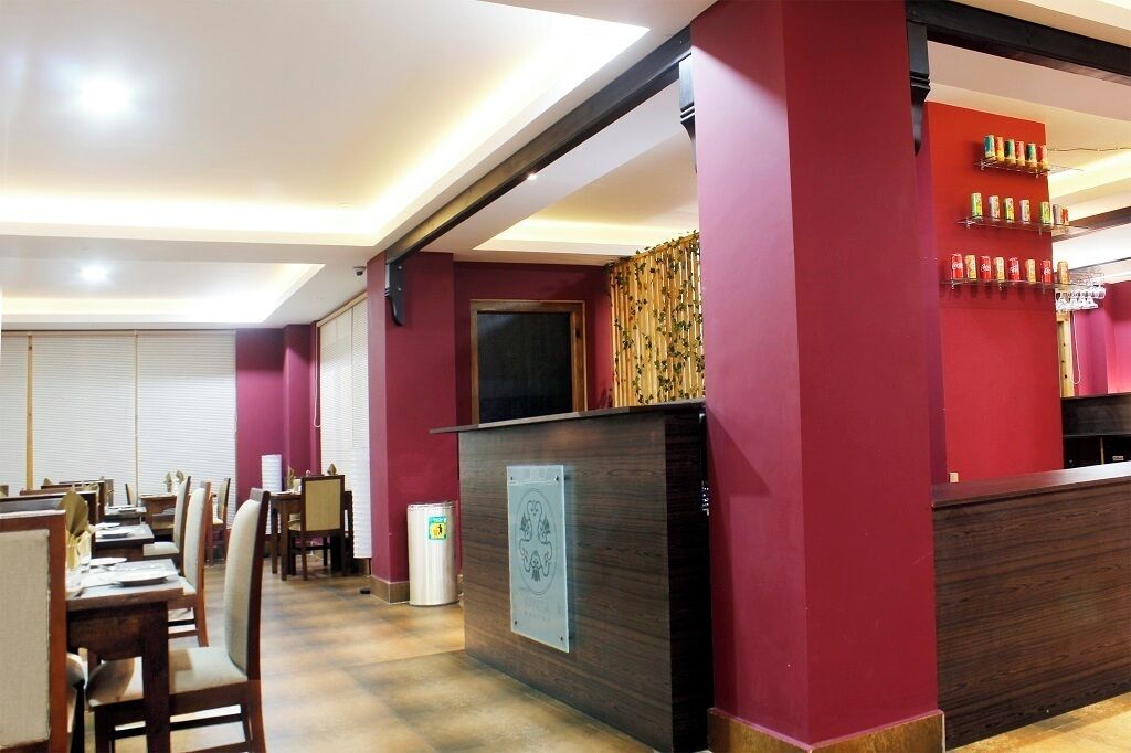 Un restaurante con mostrador de recepción, zona de estar y una pared con estantes de bebidas.
