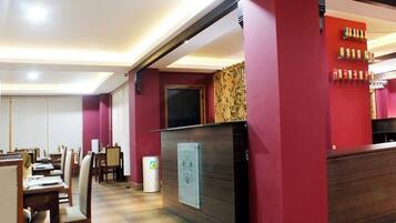 Un restaurante con mostrador de recepción, zona de estar y una pared con estantes de bebidas.