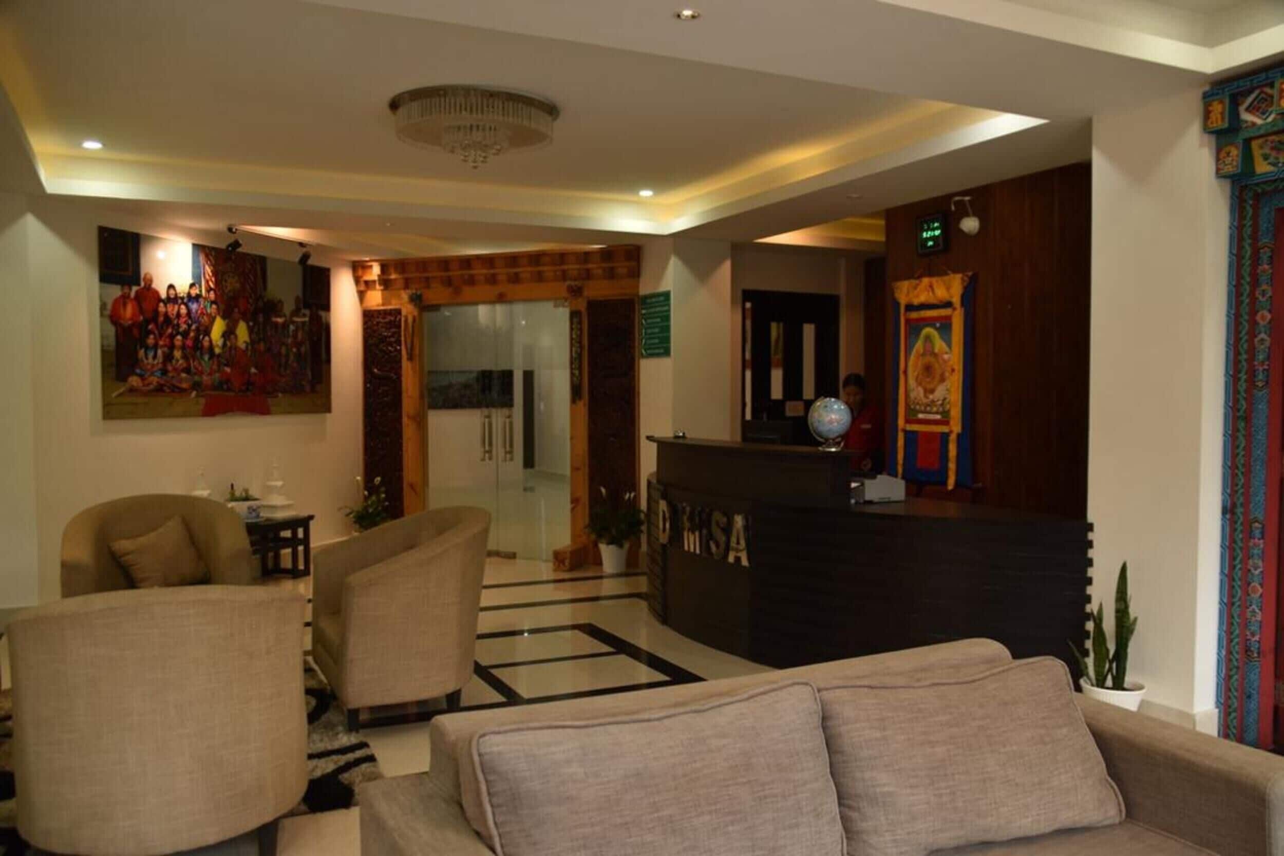 Un vestíbulo de hotel con mostrador de recepción, zona de estar y una pared con un cuadro grande enmarcado.