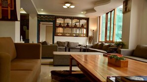 A cozy living room with a sofa, armchairs, a wooden coffee table, and a decorative mirror.