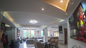 A spacious lobby with a reception desk, seating area, and large windows allowing natural light.