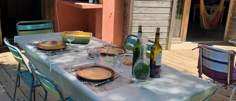 Eine Holzterrasse mit Esstisch, Gartenstühlen und einer Hängematte.