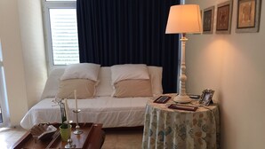 Une chambre bien rangée, avec un lit, une table de chevet, une lampe et des tableaux encadrés accrochés au mur.