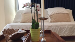 Une chambre à coucher bien rangée, avec un lit, une table de chevet ornée d’un vase vert, un bol décoratif et un grand chandelier.