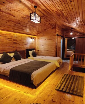 A wooden cabin bedroom with two beds, a wooden floor, and a ceiling light fixture.