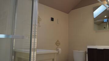 A bathroom with a glass shower enclosure, a toilet, and a dark wooden cabinet.