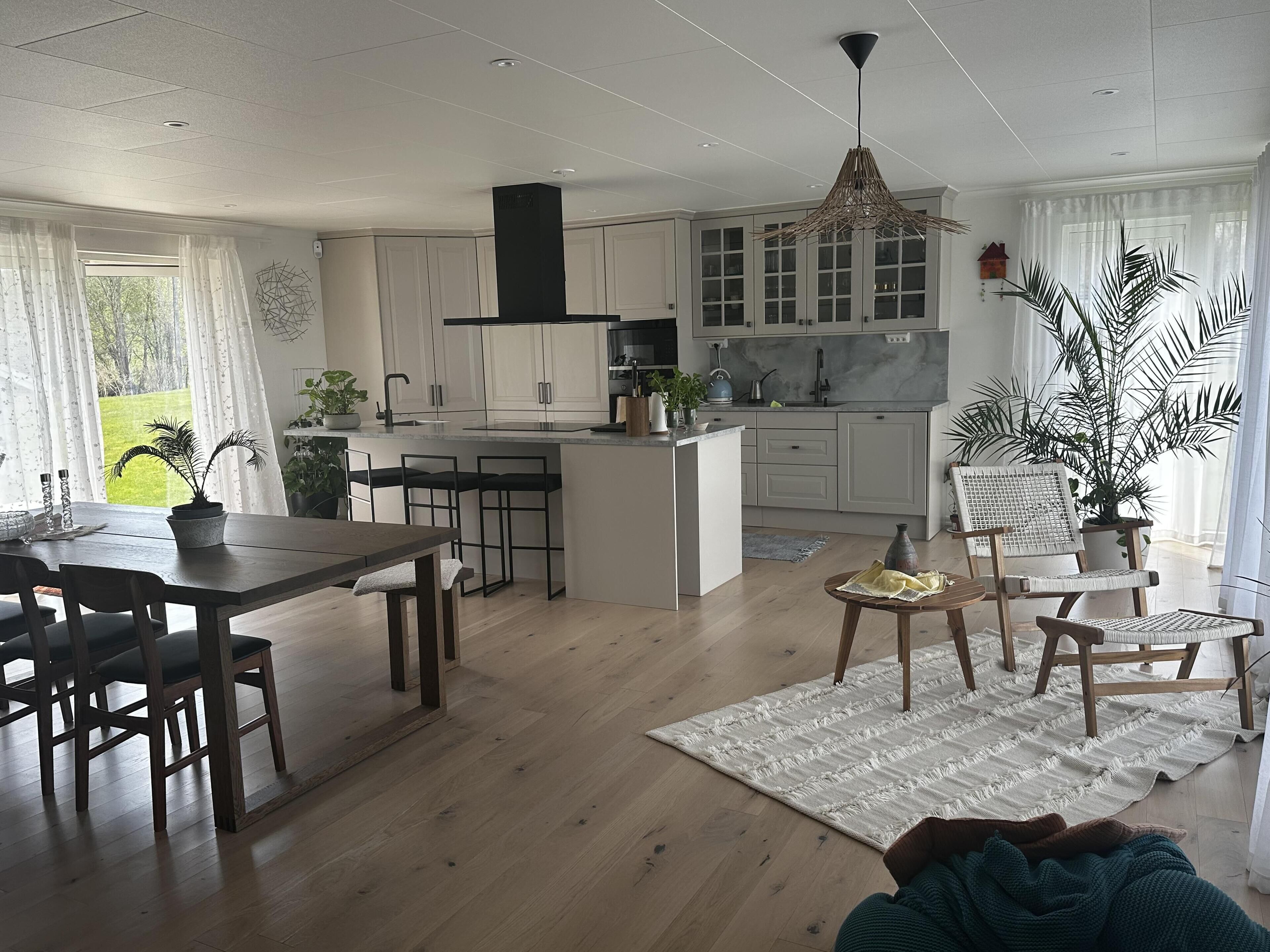 A modern kitchen with white cabinets, a central island, and a dining area with a wooden table and chairs.