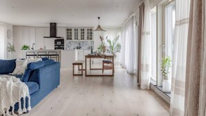 Un salon moderne avec un canapé bleu, une table à manger en bois et une cuisine en arrière-plan.