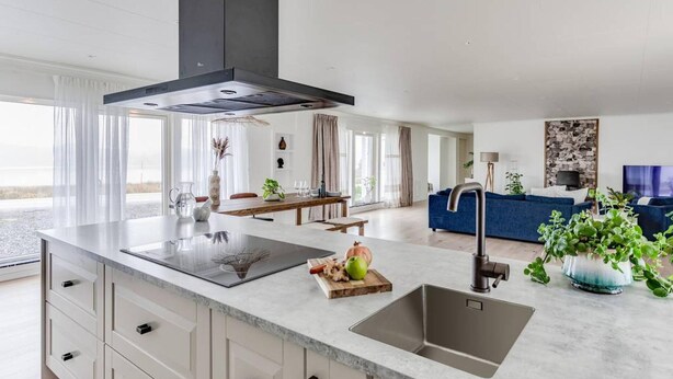 Une cuisine moderne dotée d’un grand îlot central, de meubles encastrés et d’un élégant évier en acier inoxydable.