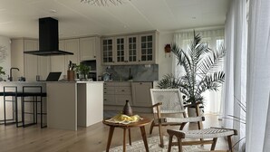 Une cuisine moderne avec des meubles blancs, une hotte noire et un îlot central doté de tabourets de bar.