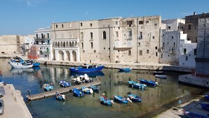 A harbor with boats docked and a historic building with arches in the background.