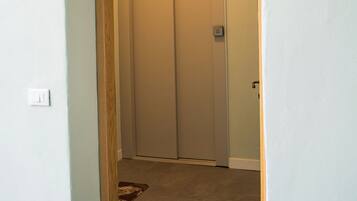 Un couloir étroit, avec un tapis à l’entrée et une porte dotée d’un interrupteur.