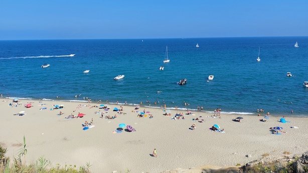 A beach with numerous people, colorful umbrellas, and boats on the water. - Agréable T2 Avec vue sur la mer (Leucate)