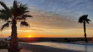 A sunset view over a swimming pool area with palm trees and a distant horizon. - Agréable T2 Avec vue sur la mer (Leucate)