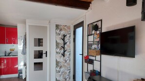 A modern kitchen with red cabinets, a black countertop, and a wooden ceiling. - Agréable T2 Avec vue sur la mer (Leucate)