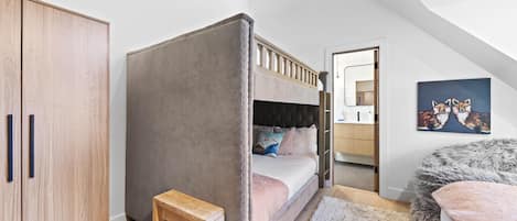 Un dormitorio con una cama litera, un armario de madera, un taburete pequeño de madera, una alfombra mullida y un cuadro en la pared.