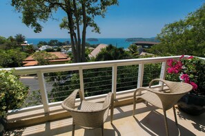 A balcony with wicker chairs, a railing, and a view of the sea and buildings. - Katamanda Villa Jade A6 Seaview Kata Beach (Muang Phuket)