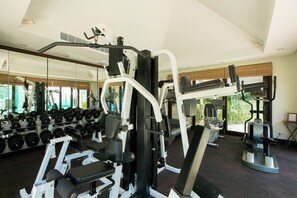 Uma academia com diversos equipamentos de exercícios, suportes para pesos e um espelho grande na parede.