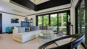 A modern living room with a sectional sofa, a round coffee table, and a black chair. - Katamanda Villa Jade A6 Seaview Kata Beach (Muang Phuket)