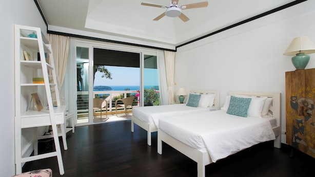 A bedroom with two beds, a ceiling fan, a view of the sea, and a balcony with a chair. - Katamanda Villa Jade A6 Seaview Kata Beach (Muang Phuket)