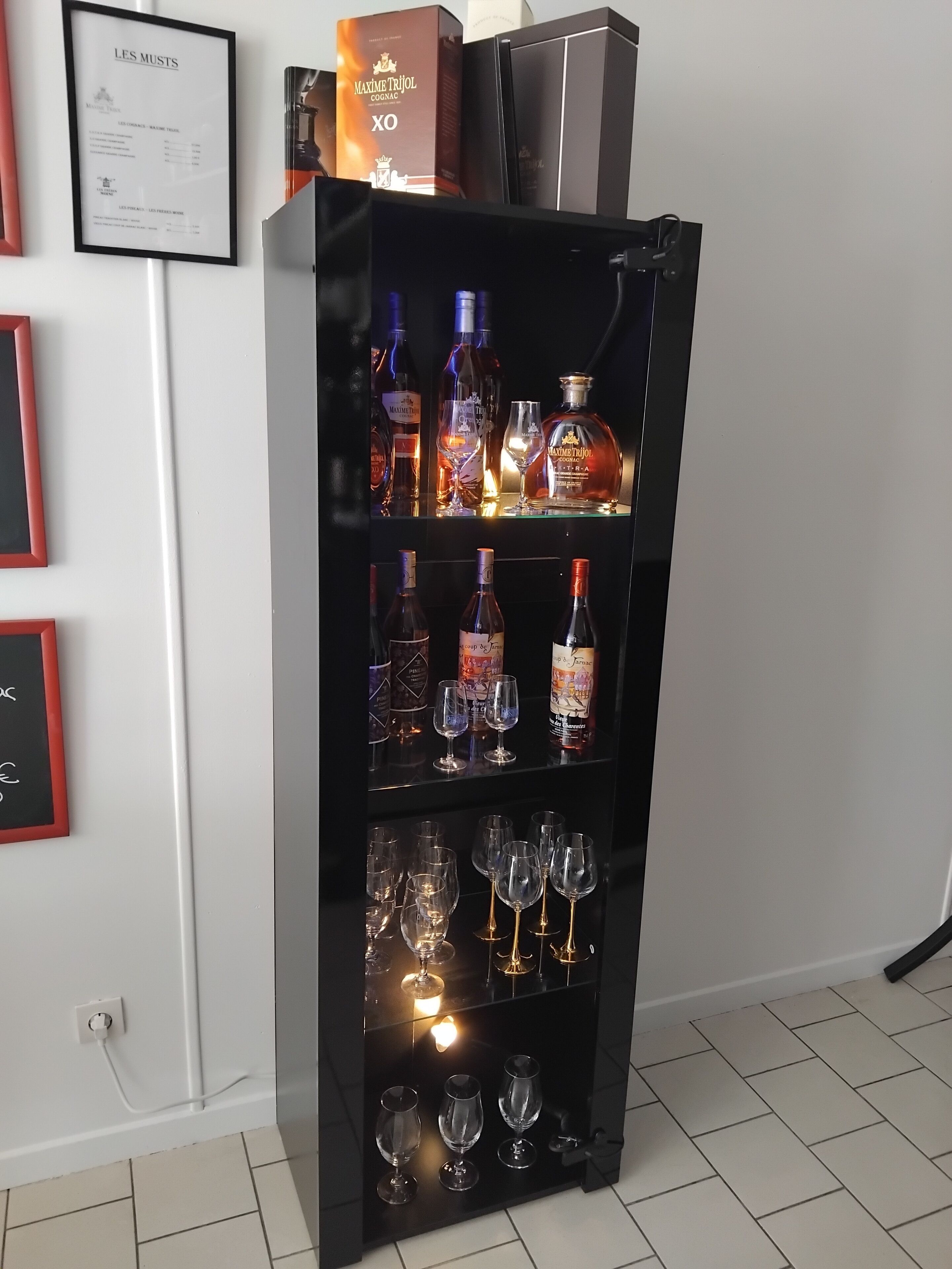 Een drankenkast met meerdere planken, gevuld met flessen en glazen.