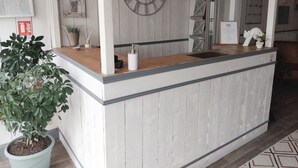 Una recepción con mostrador de madera, un reloj en la pared y una planta en maceta.