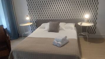 A modern hotel room with a large bed, two bedside tables with lamps, a patterned wall, and a ceiling light.