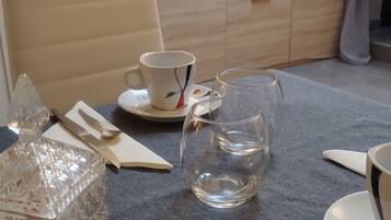 A dining area with a table set for two, featuring a clear glass, a white cup, and a crystal decanter.