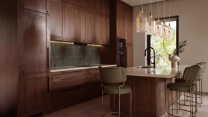 Uma cozinha moderna com armários de madeira escura, uma ilha central com banquetas e iluminação pendente.