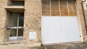 A building with a large garage door, a small window, and a doorbell.