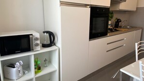 A compact kitchenette with a microwave, toaster, kettle, and a small sink.