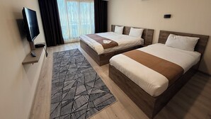 A hotel room with two beds, a TV, an air conditioner, and a window with curtains. - Rena Grand Residence & Suite (Yomra)