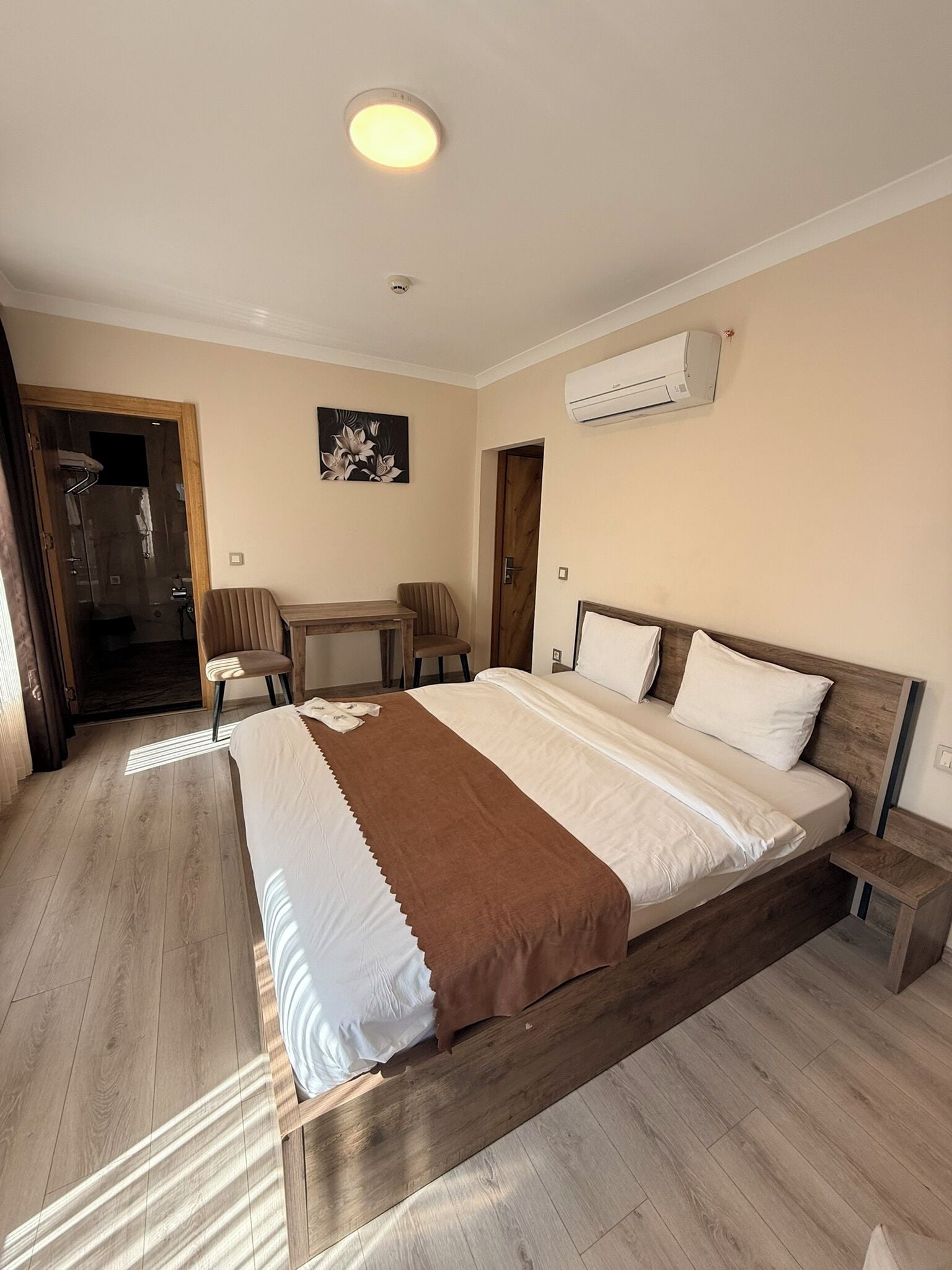 Ein Hotelzimmer mit einem großen Bett, einem Schreibtisch, einem Stuhl, einer Klimaanlage und einem Duschbereich.