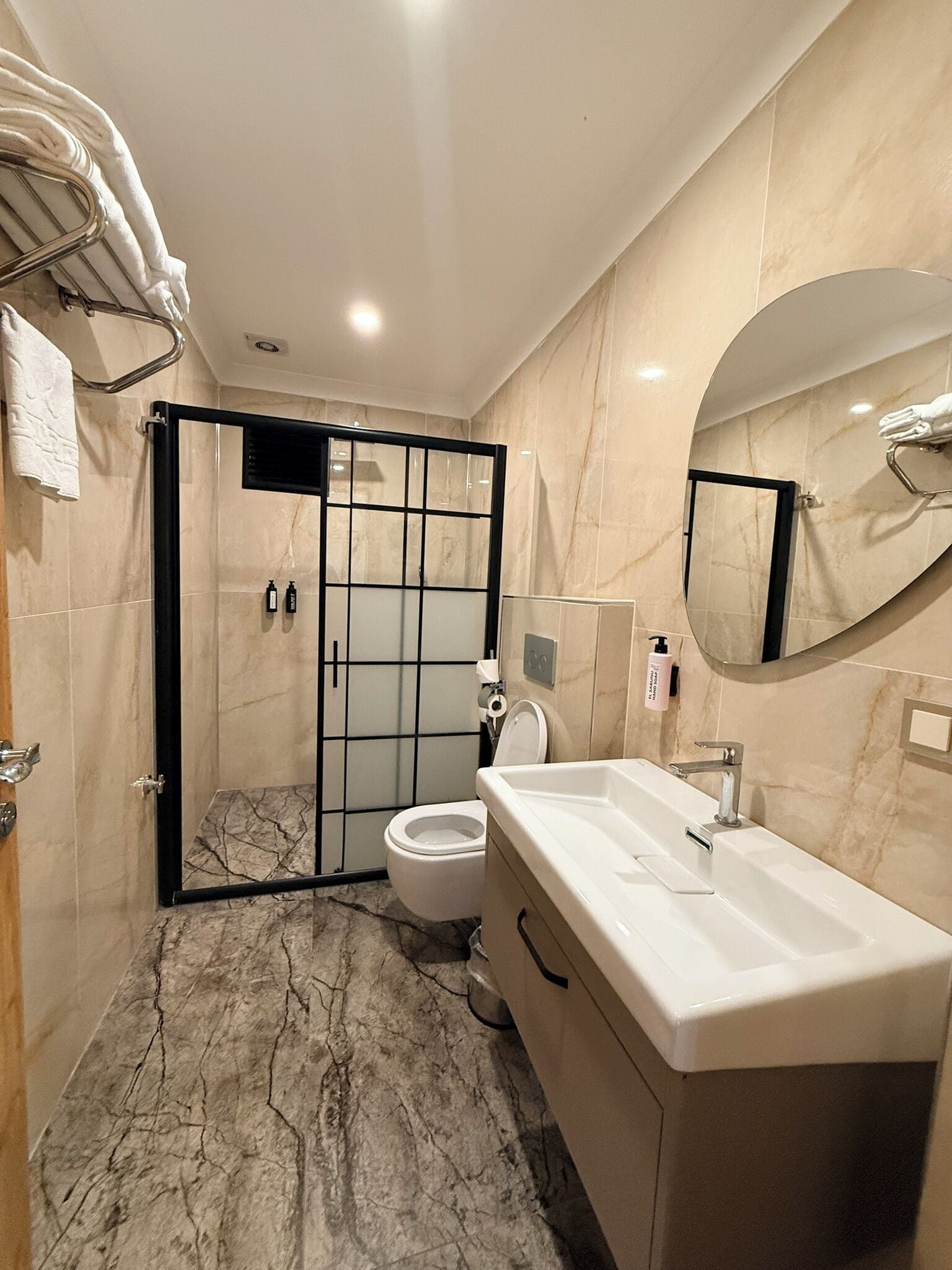 A bathroom with a shower enclosure, toilet, sink, and a large mirror.