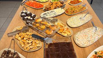 A buffet table with various food items and utensils.