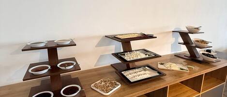 A wooden buffet table with multiple serving dishes and a shoe rack.