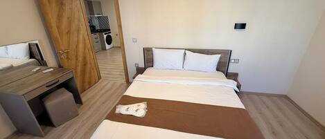 Habitació d'hotel amb un llit, un escriptori, una cadira, un aparell d'aire condicionat i una porta que dóna a una zona de bugaderia.