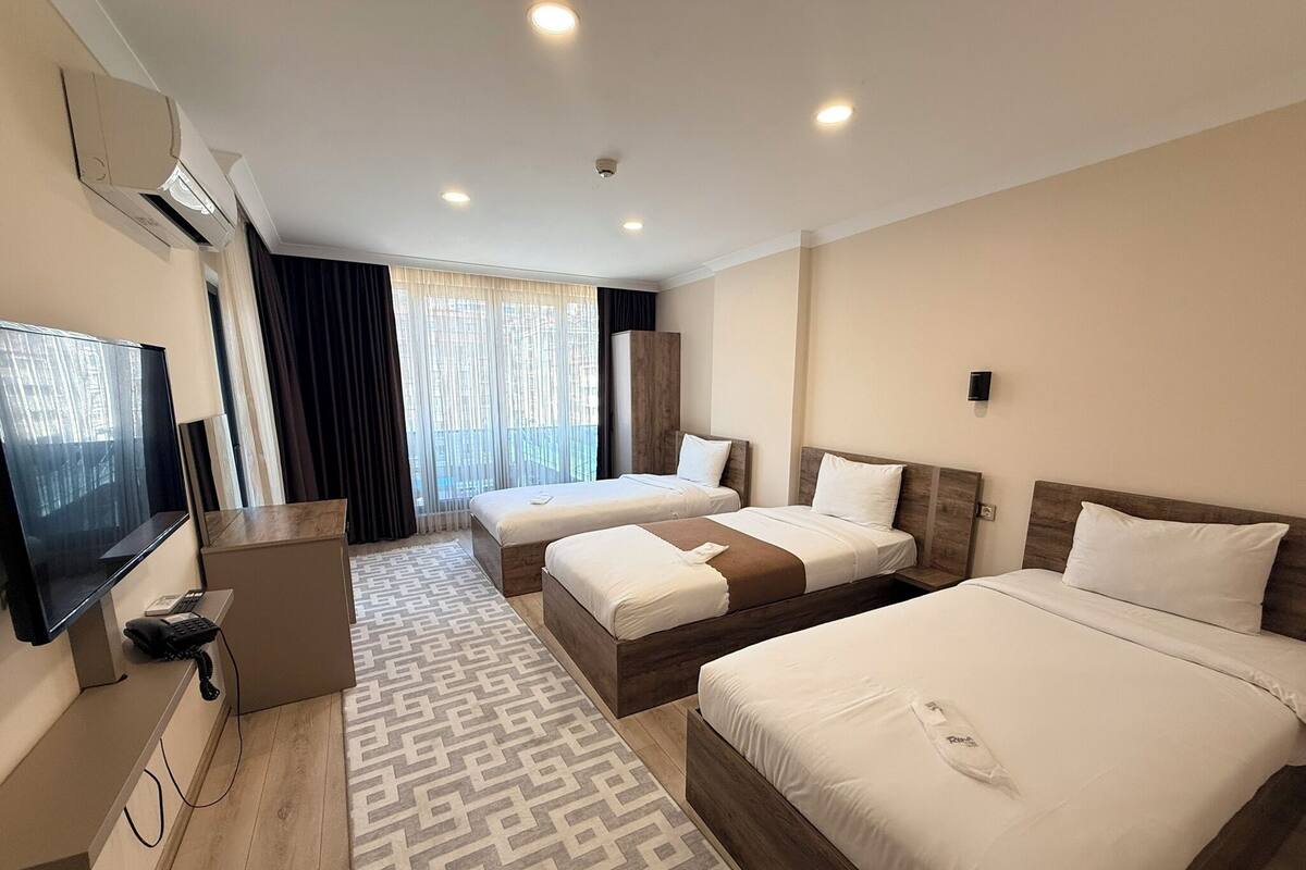 A hotel room with two beds, a TV, a desk with a phone, and a patterned rug.