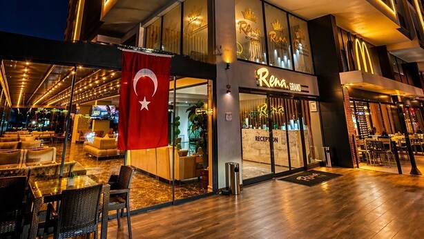 A modern hotel exterior with a reception area, outdoor seating, and a flag. - Rena Grand Residence & Suite (Yomra)