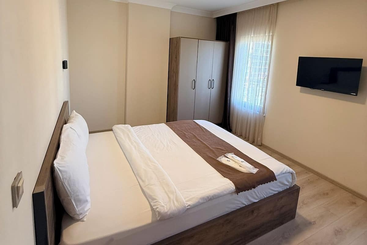 A modern hotel room with a bed, wardrobe, TV, and air conditioning unit.