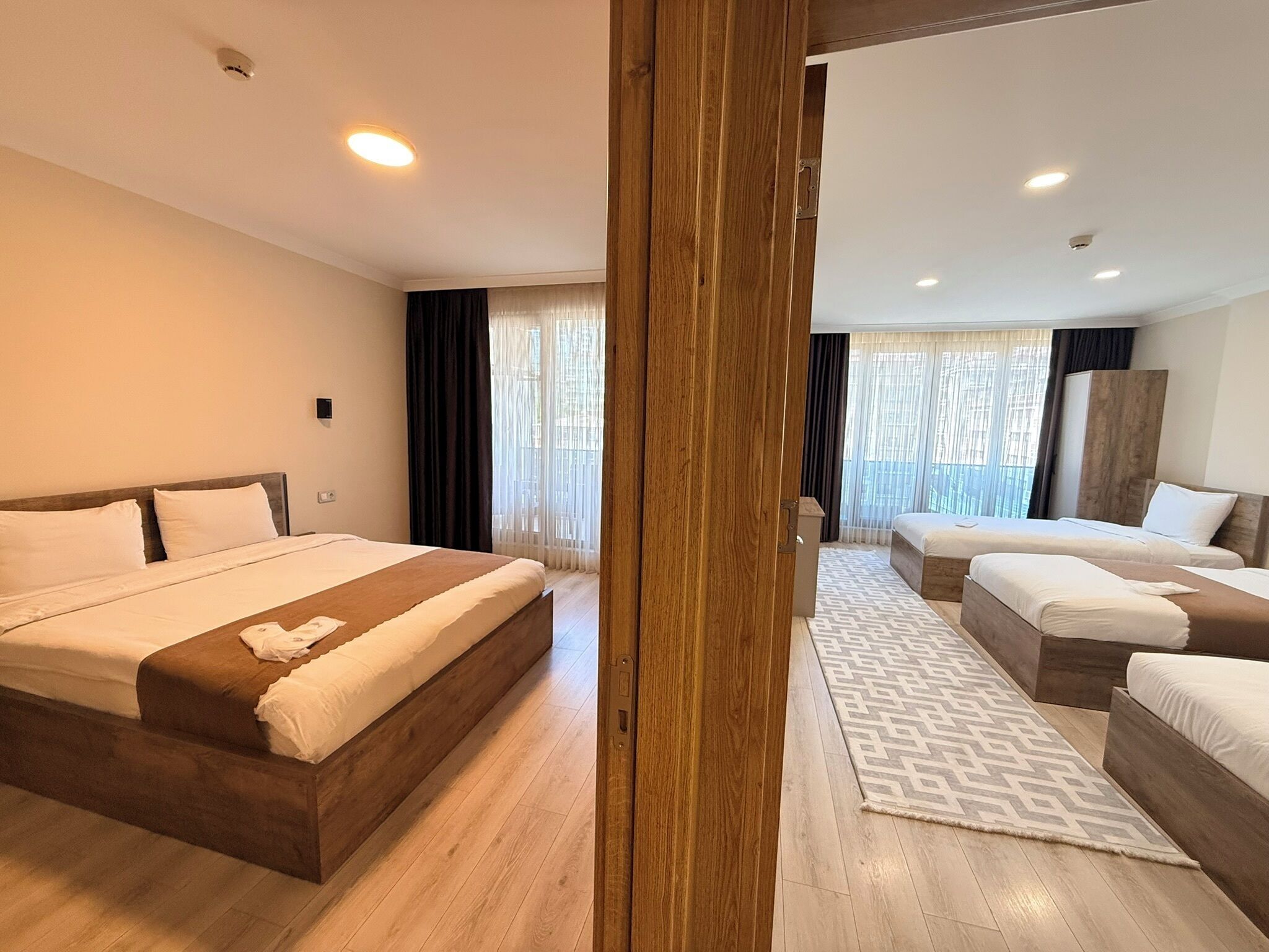 Une chambre d’hôtel avec un grand lit, un lit plus petit, une armoire et une fenêtre avec des rideaux.