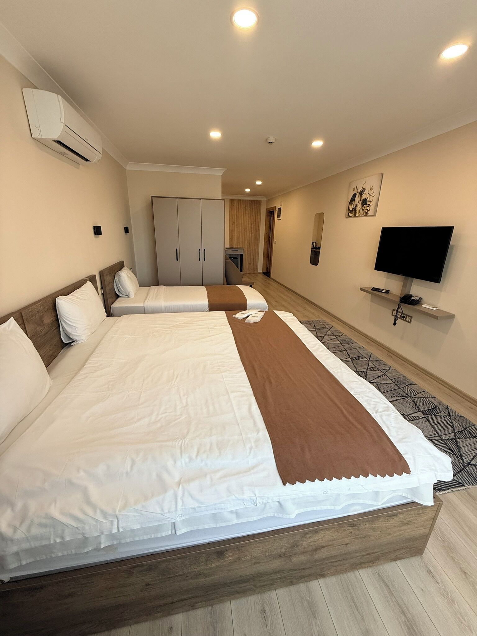 A hotel room with two beds, a TV, and a wardrobe.