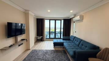 Deluxe suite, balkon, uitzicht op zee | Woonruimte | Een 120-cm flatscreentelevisie met digitale zenders