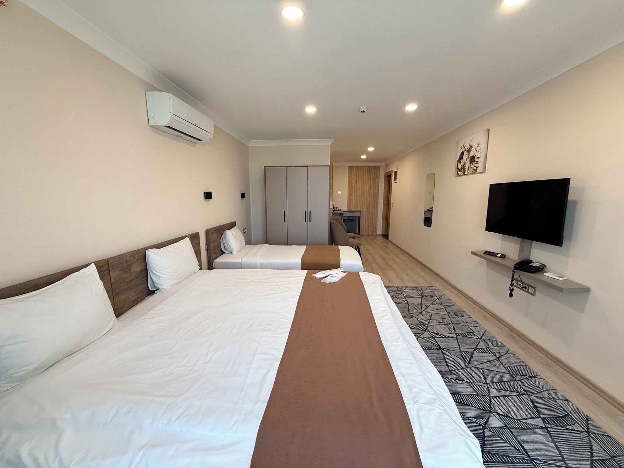 A hotel room with two beds, a TV, a desk, and a wardrobe.
